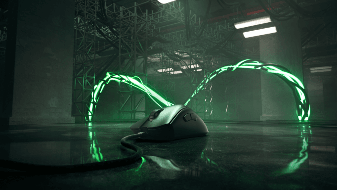 Souris DeathAdder V3 Pro noire avec câble vert luminescent sur une surface reflétante, en environnement industriel
