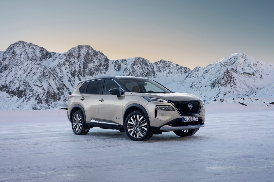 Nissan X-Trail blanc garé sur un lac gelé, montagnes enneigées en arrière-plan