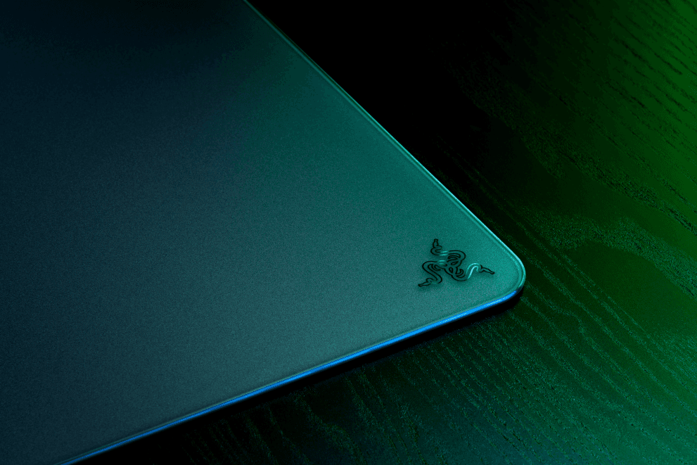 Tapis de souris Razer Atlas en verre trempé avec logo Razer, bord bleu, posé sur surface verte et noire