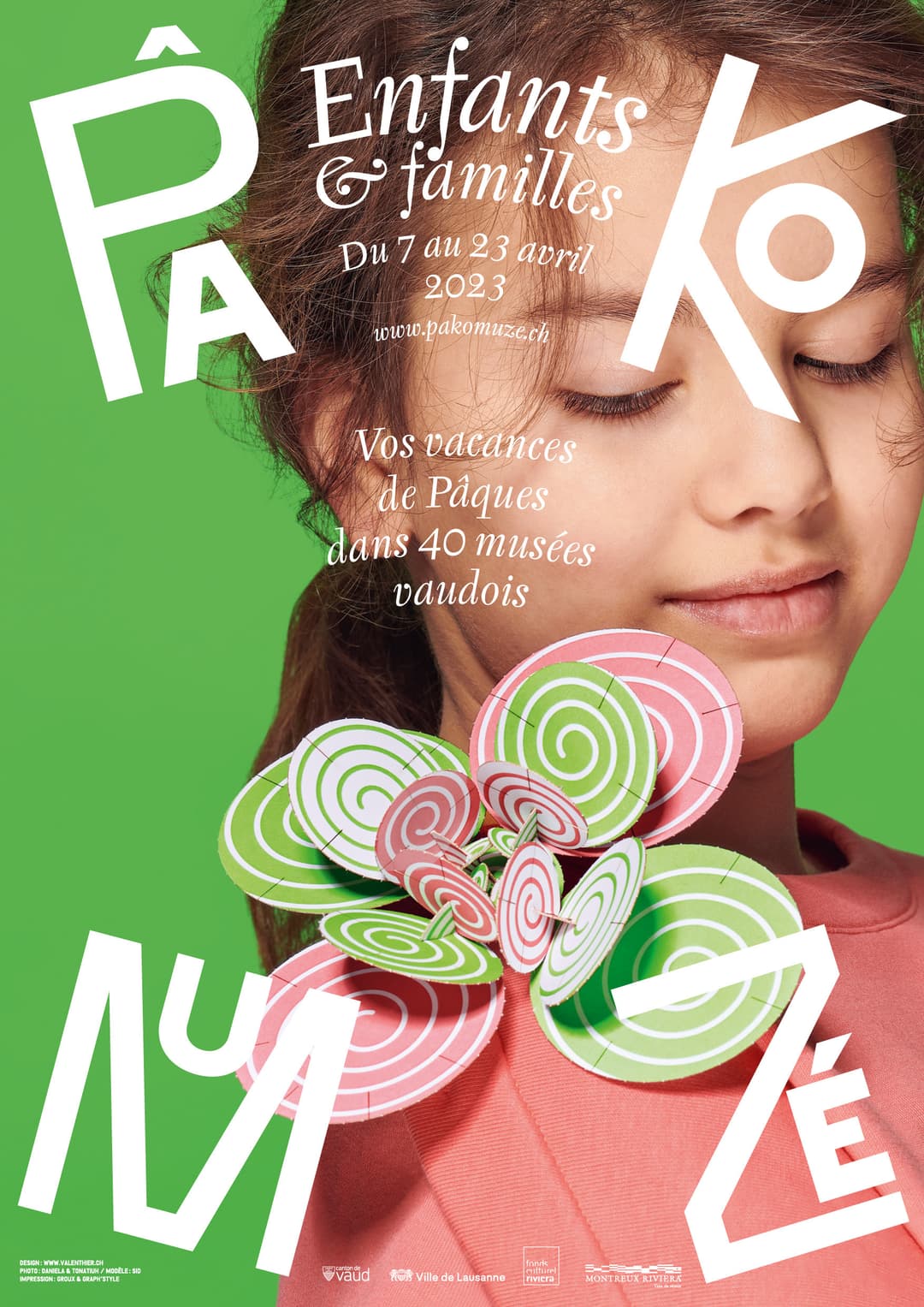 Affiche PâKOMUZé 2023 montrant un enfant souriant sur fond vert tenant des sucettes colorées roses et vertes