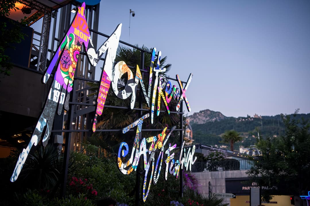 Sculpture colorée de guitares géantes aux motifs fluo et arc-en-ciel, installée à Montreux devant les montagnes et le lac