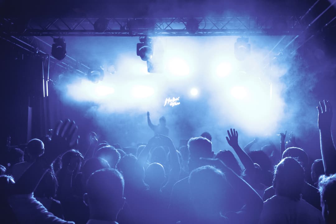 Foule de spectateurs face à la scène du Montreux Jazz Festival, baignée de lumières bleues intenses