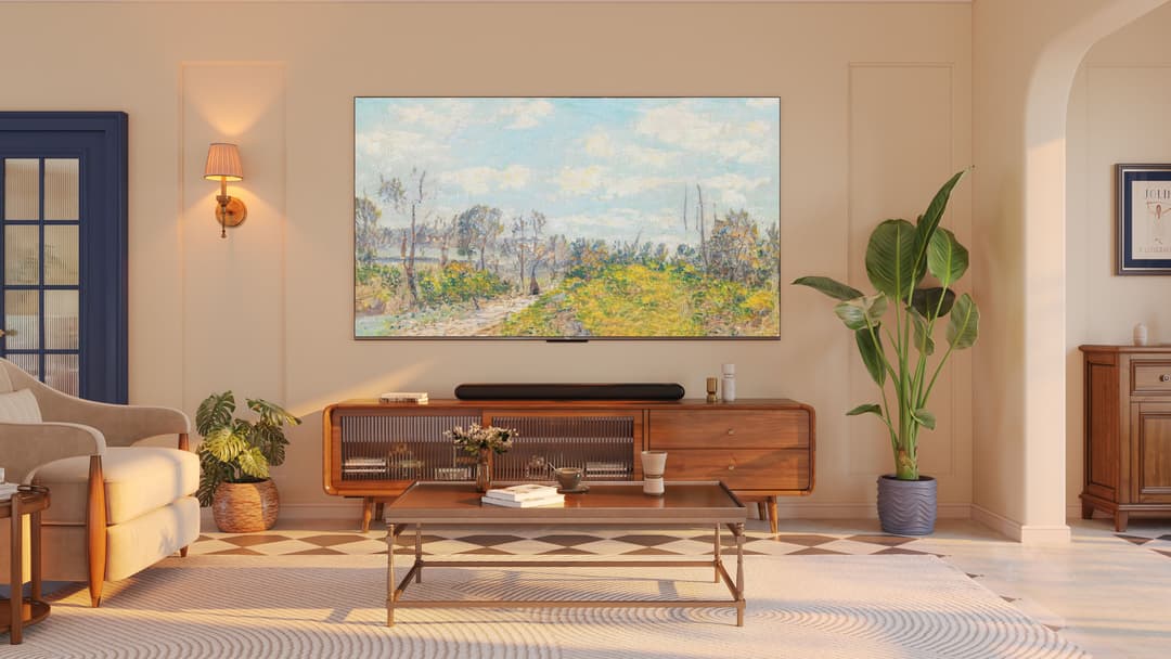 Téléviseur TCL QLED série C64 affichant un paysage champêtre accroché au-dessus d'un meuble en bois dans un salon contemporain