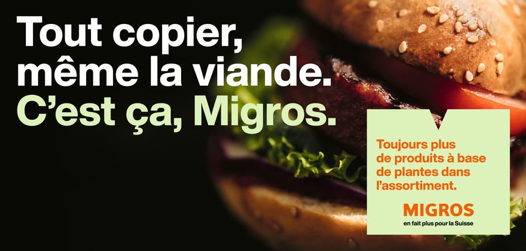 Affiche Migros avec hamburger garni et texte blanc « Tout copier, même la viande. C'est ça, Migros » accompagné du slogan « en fait plus pour la Suisse »