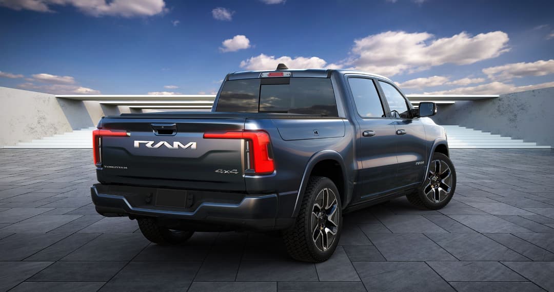 Ram 1500 REV électrique 2025 de profil sur un parking, carrosserie gris métallisé avec feux arrière rouges