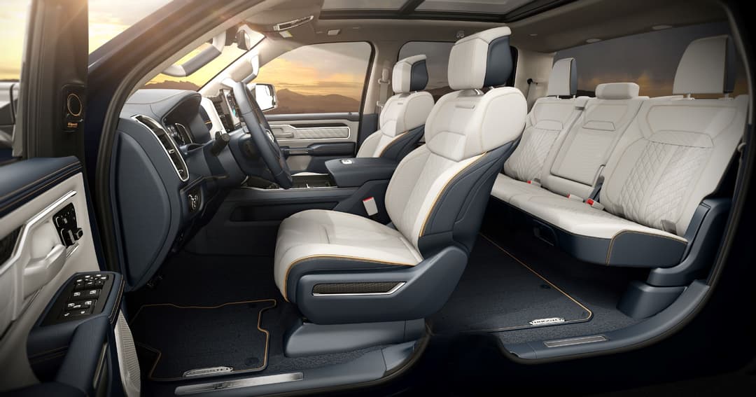 Intérieur du Ram 1500 REV 2025 avec sièges bicolores crème et noir, volant noir et tableau de bord moderne