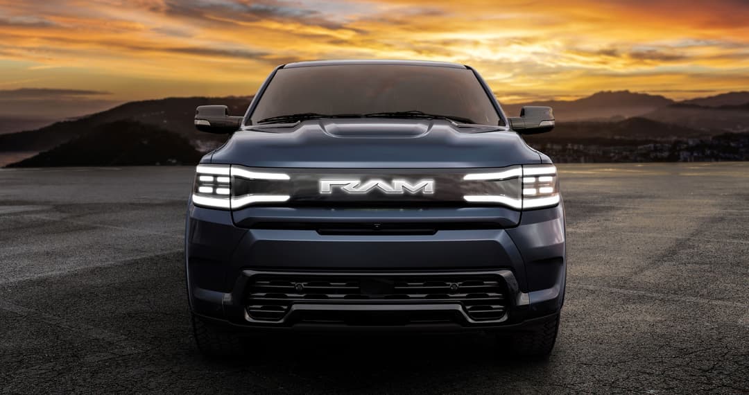 Ram 1500 REV électrique noir de face, phares LED allumés, au coucher du soleil