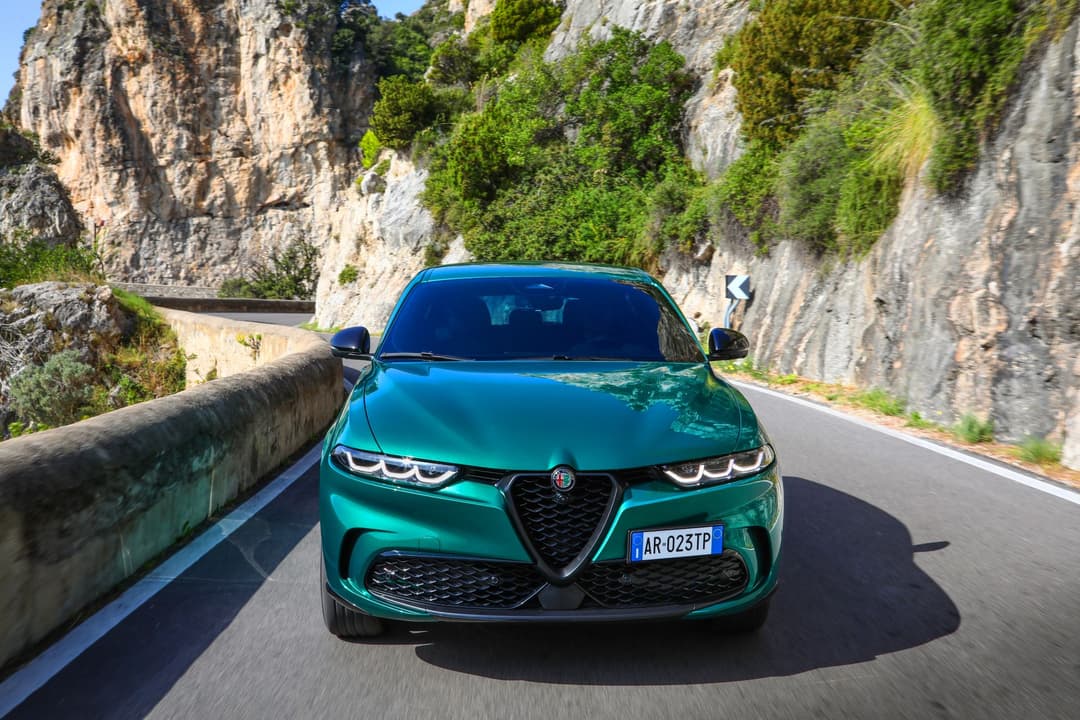 Alfa Romeo Tonale Hybride Rechargeable vert circulant sur une route sinueuse en montagne entre des falaises rocheuses