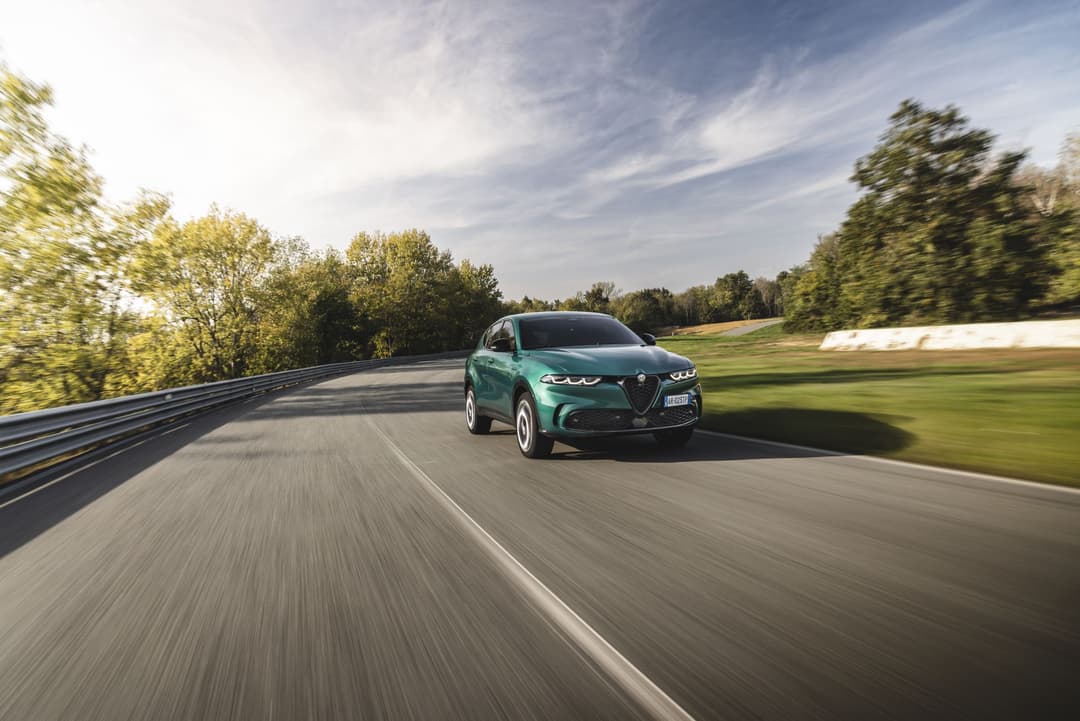 Alfa Romeo Tonale Hybride Rechargeable vert en mouvement sur autoroute avec arbres en arrière-plan