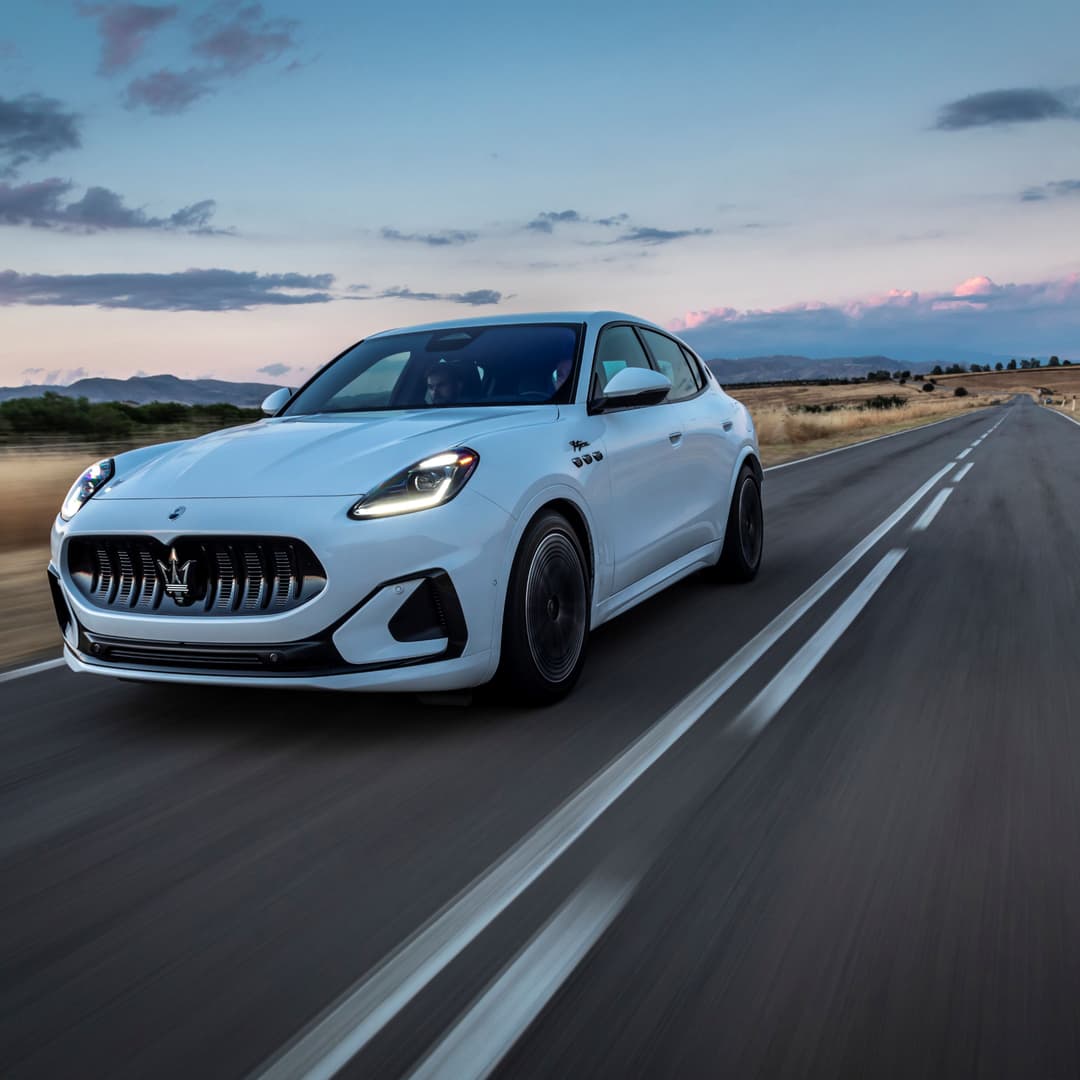 Maserati Grecale Folgore blanc sur une route déserte au coucher du soleil, paysage aride en arrière-plan