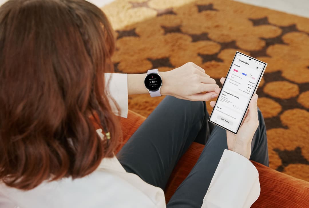 Femme consultant une Galaxy Watch5 blanche affichant les données de suivi menstruel synchronisées avec son smartphone