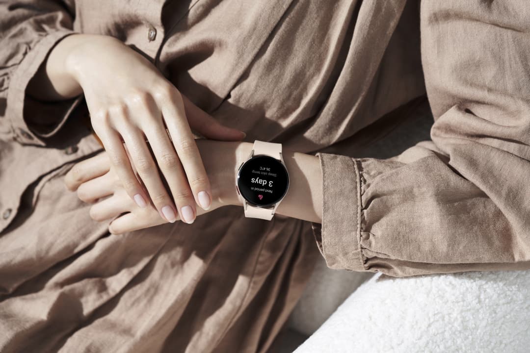 Samsung Galaxy Watch5 au bracelet blanc affichant l'application Cycle Tracking au poignet d'une femme