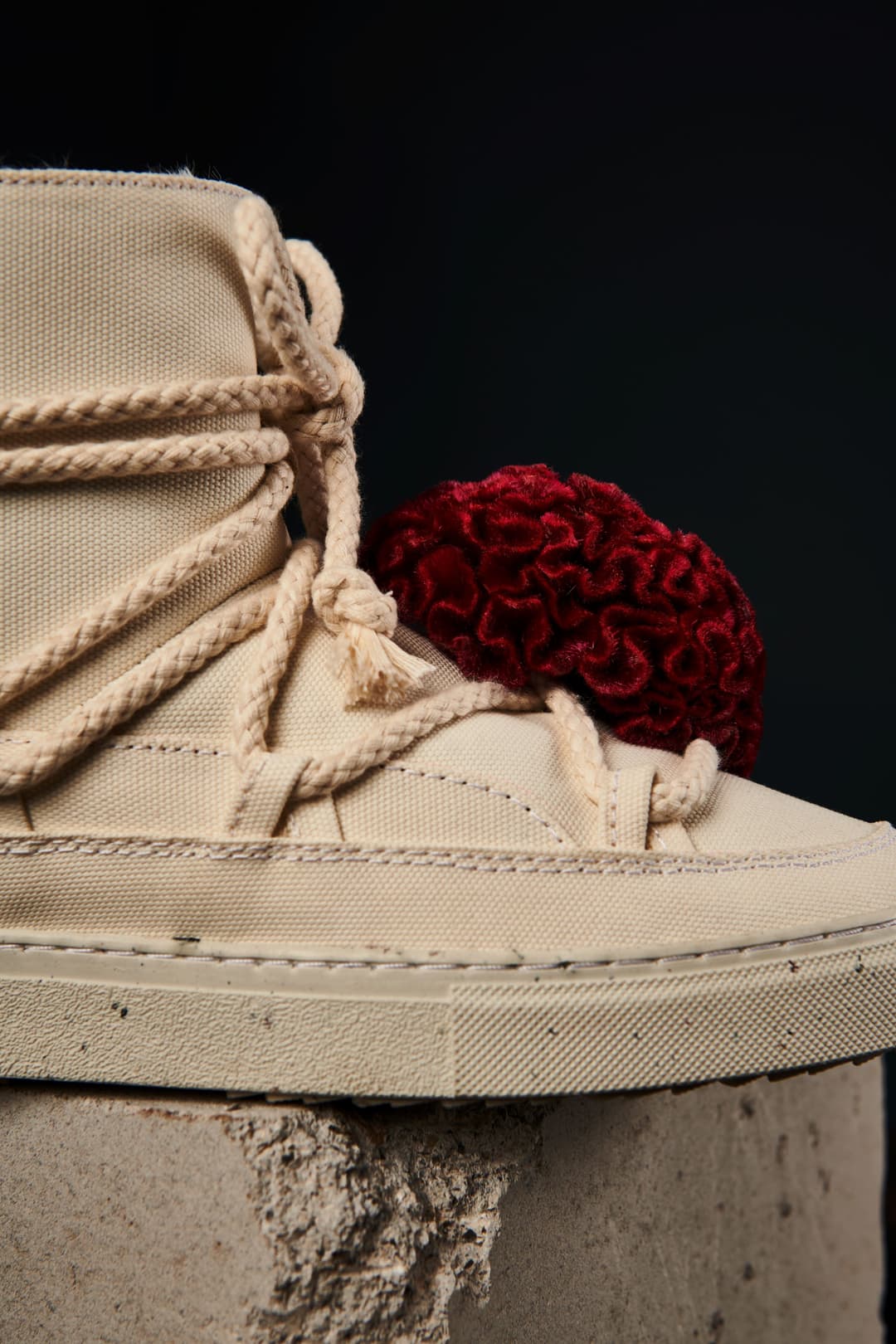 Détail d'une chaussure INUIKII beige avec lacets en corde et décoration rouge, montrant le matériau Vegea issu du marc de raisin