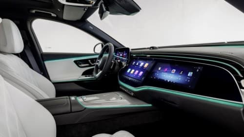 Intérieur de la Mercedes Classe E avec tableau de bord futuriste, super-écran MBUX bleu et vert, volant, sièges blancs