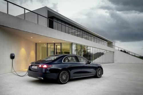 Classe E noire en recharge devant un bâtiment moderne aux façades blanches