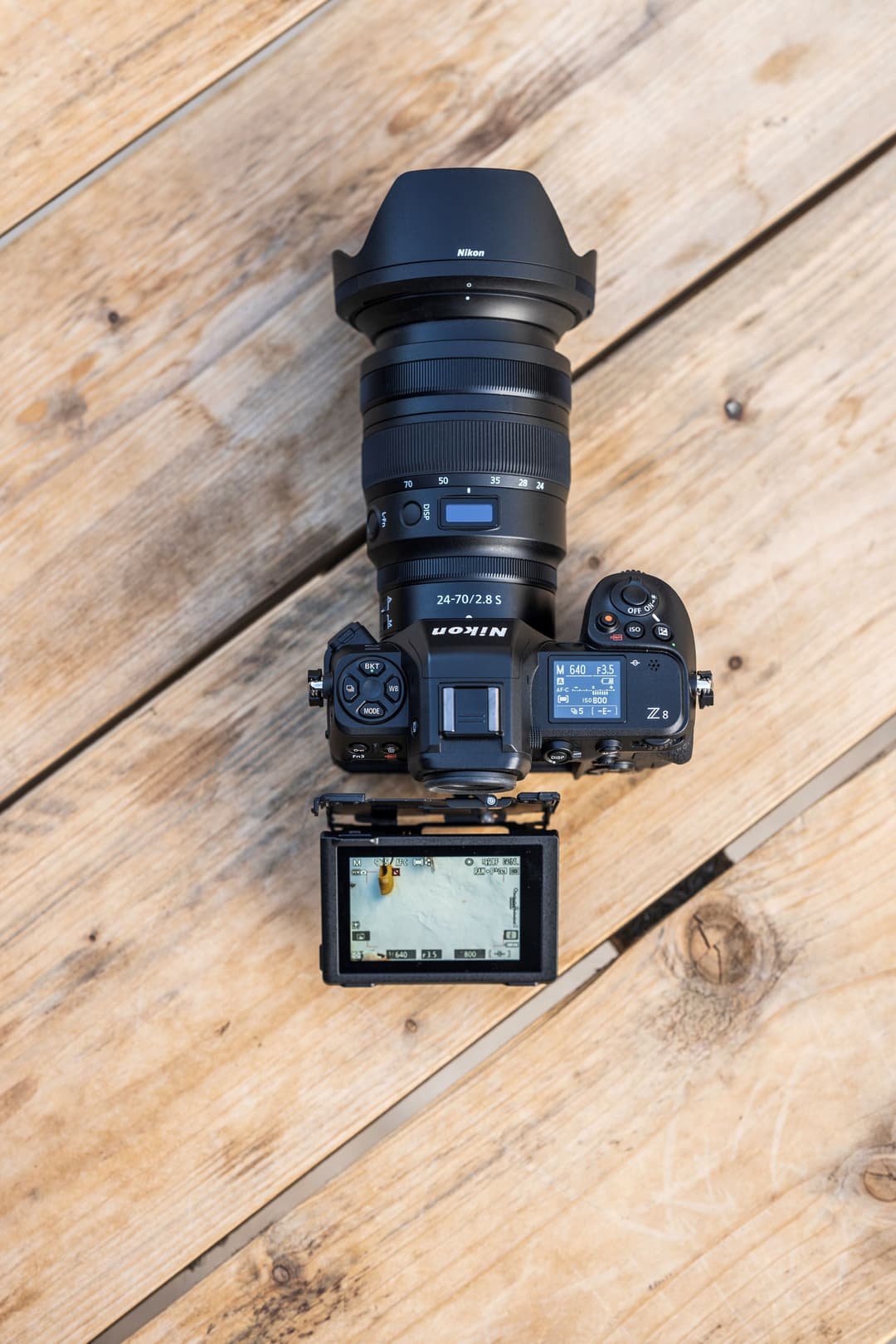 Nikon Z 8 monté avec un objectif 24-70mm et un écran externe, vue de dessus sur un parquet clair