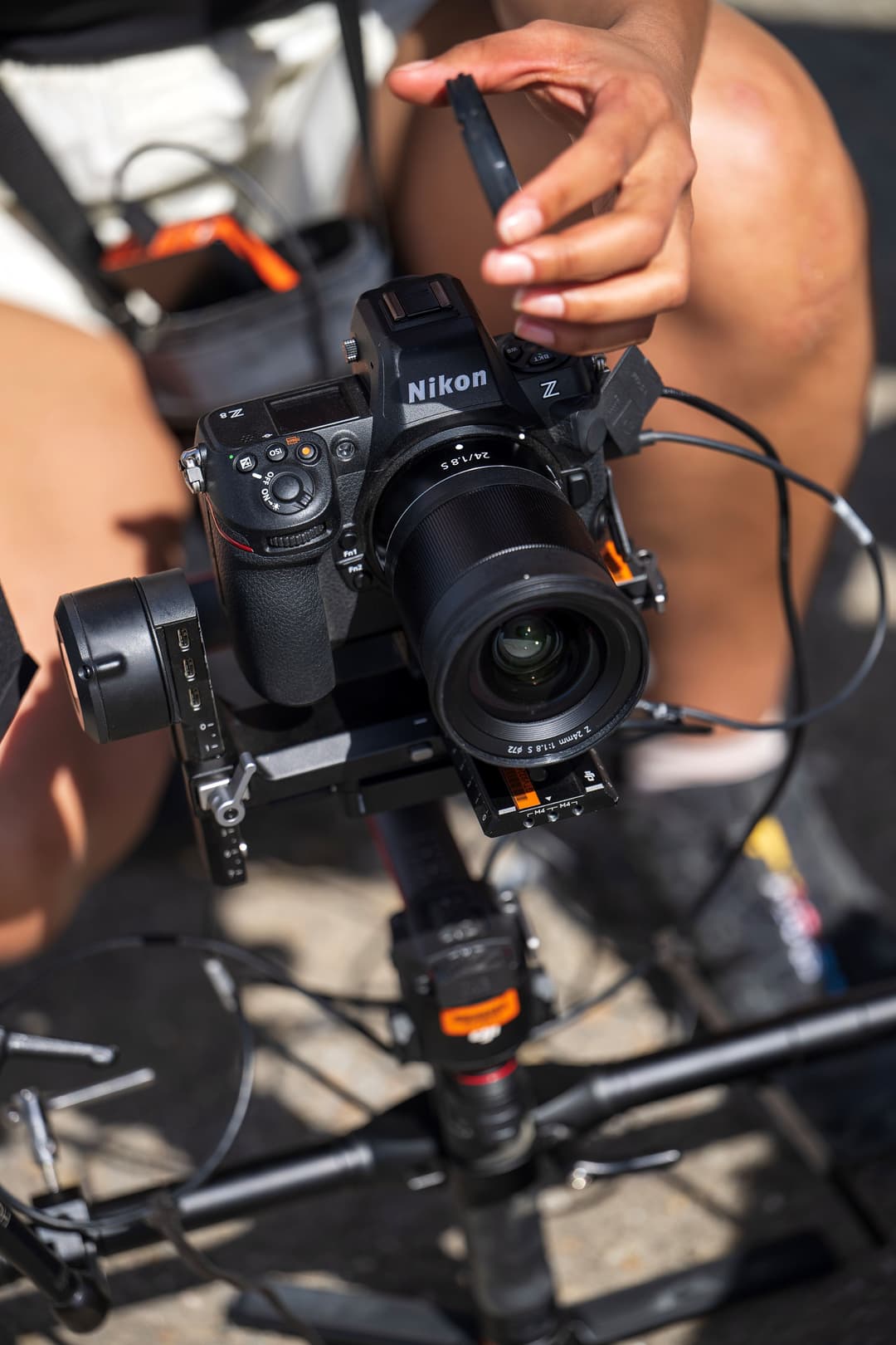 Appareil photo Nikon Z 8 noir équipé de la poignée-alimentation MB-N12 orange, tenu en main avec accessoires