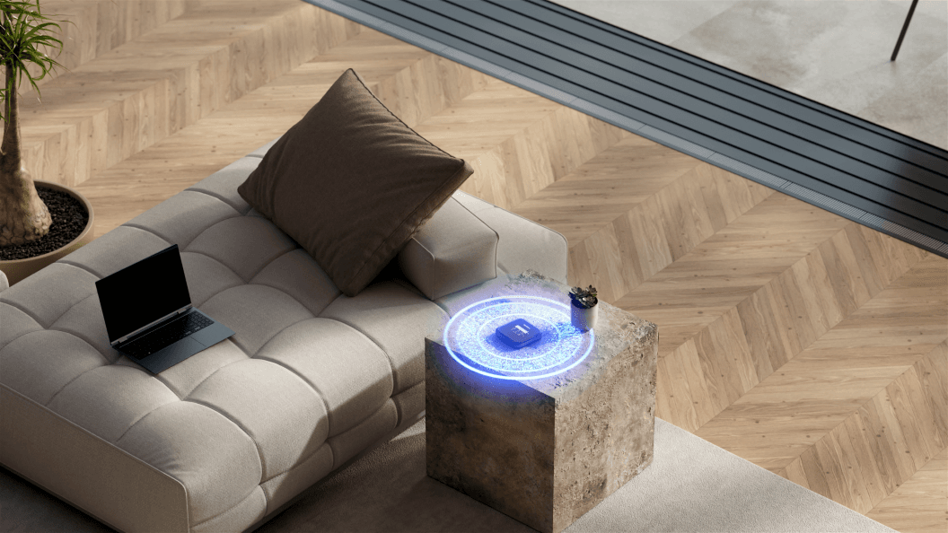 Routeur mobile NETGEAR affichant une projection lumineuse bleue, posé sur un cube en béton près d'un canapé blanc avec un ordinateur portable