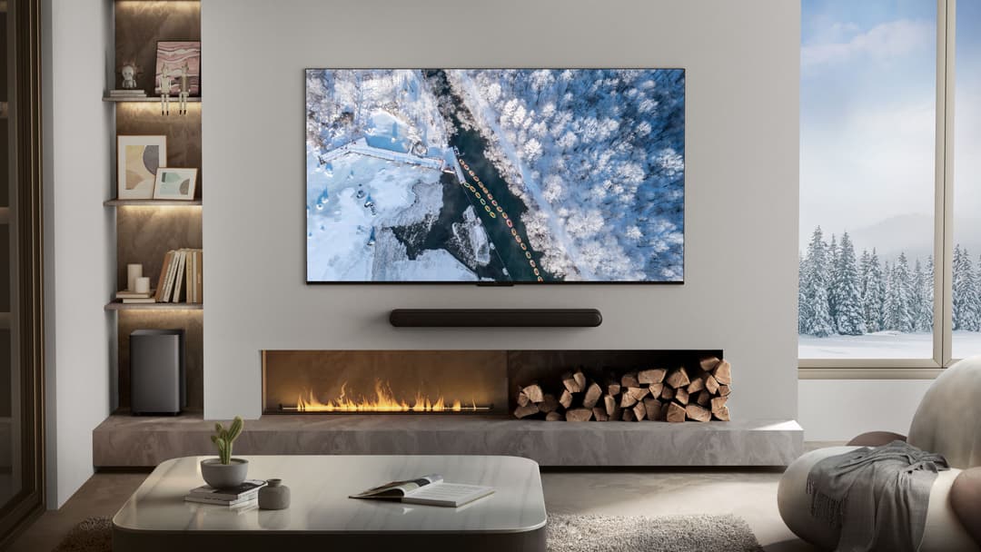 Téléviseur TCL P74 affichant un paysage enneigé, installé au-dessus d'une cheminée électrique dans un salon moderne