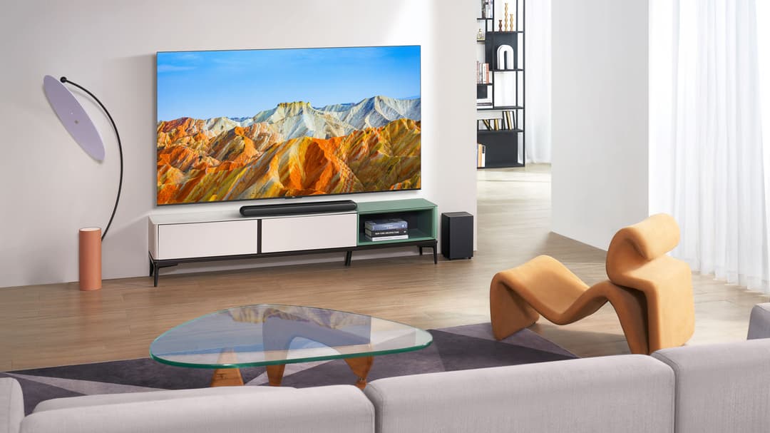 Téléviseur TCL P74 affichant des montagnes colorées, installé dans un salon moderne avec canapé et mobilier design