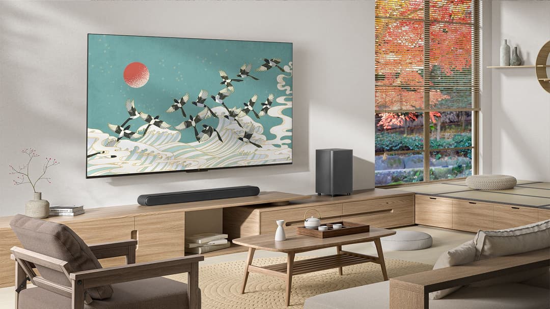 Téléviseur TCL P74 affichant un paysage asiatique stylisé avec oiseaux et lune rouge, installé au-dessus d'une barre de son Onkyo dans un salon moderne