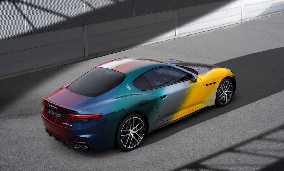 Maserati GranTurismo Prisma S aux couleurs dégradées bleu, rose et jaune, vue de trois quarts arrière sur asphalte