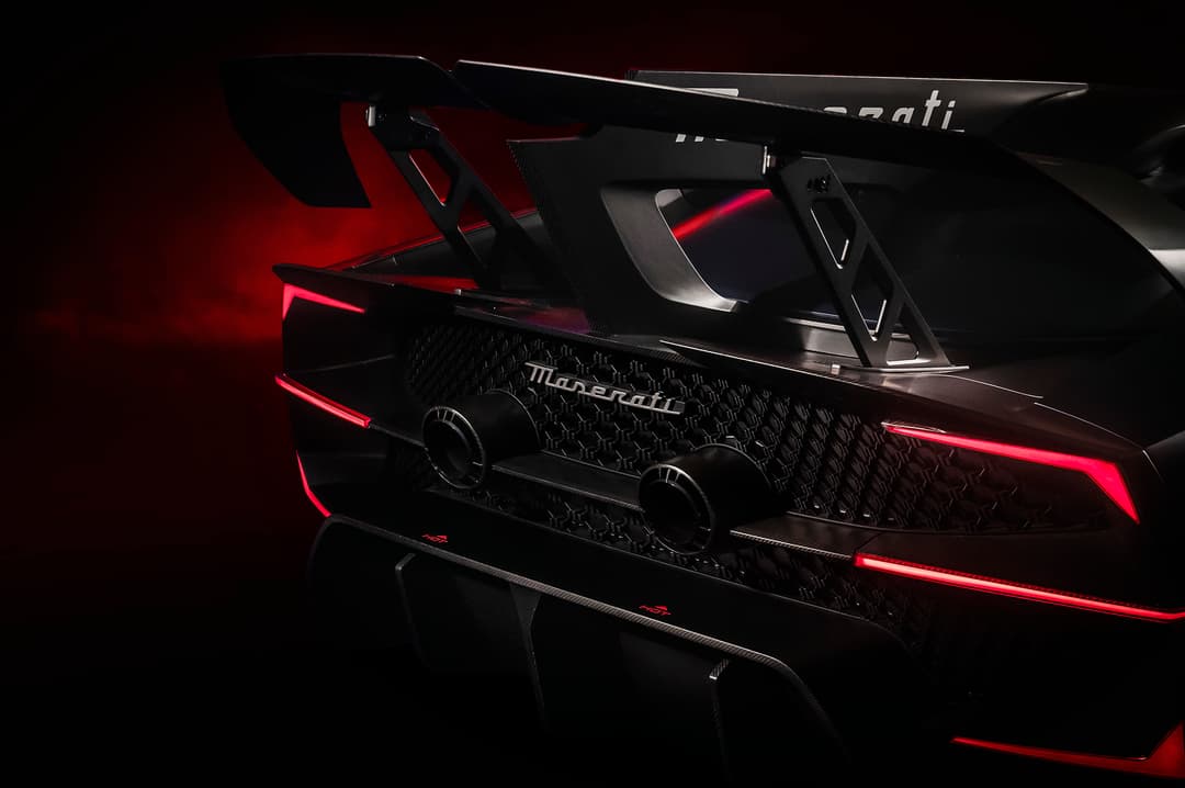 Maserati MCXtrema noir et rouge de profil, avec phares et accents lumineux rouges, sur fond noir