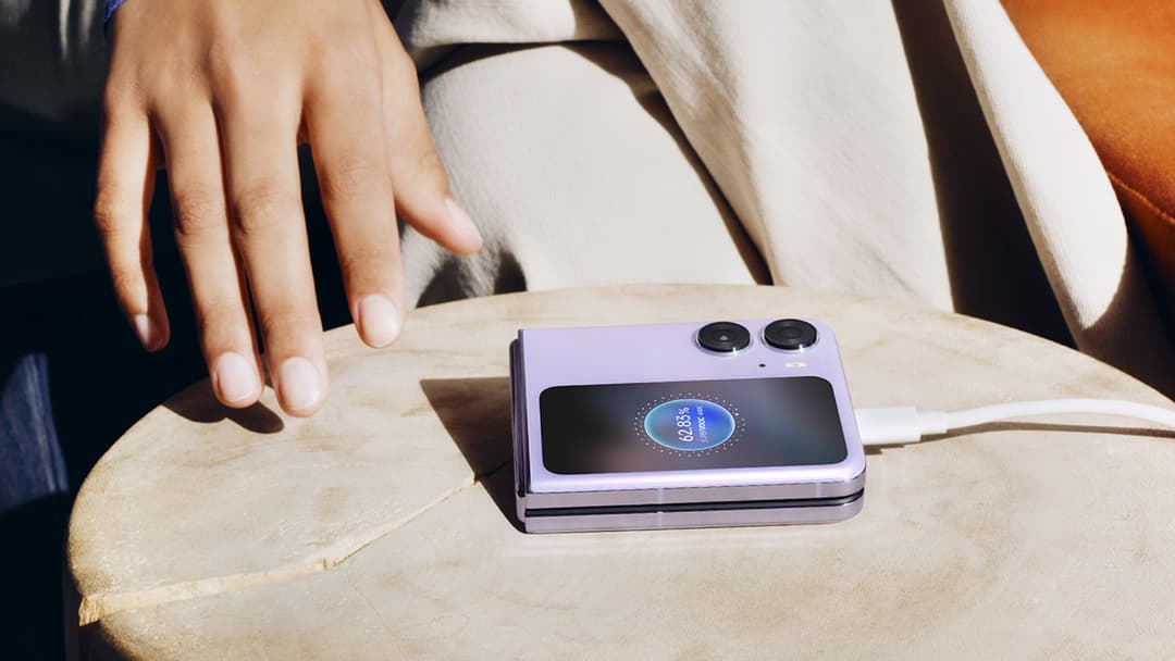 Smartphone pliable OPPO de couleur lilas posé sur une table en bois, écran allumé affichant une interface, main à proximité