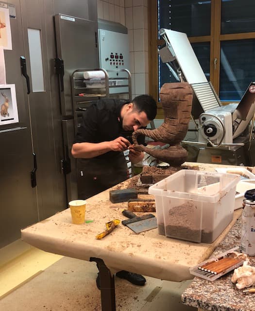 Jorge sculptant une pièce de chocolat en atelier, concentré sur son travail de maître chocolatier