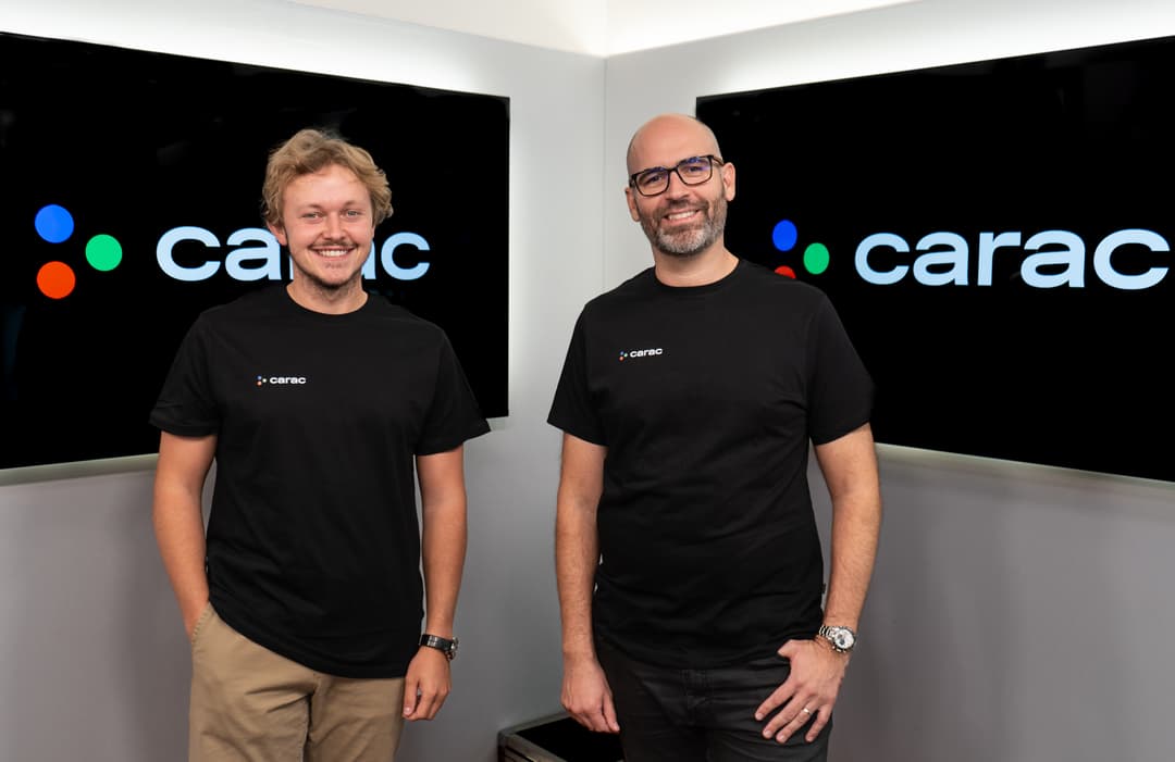 Elliot Marchal et Alexandre de Raemy posent devant des écrans affichant le logo de CARAC, vêtus de t-shirts noirs