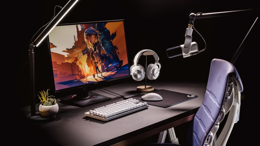 Bureau de gaming avec écran affichant un jeu d'action, clavier et souris Logitech G, casque sans fil, microphone et chaise gamer violette