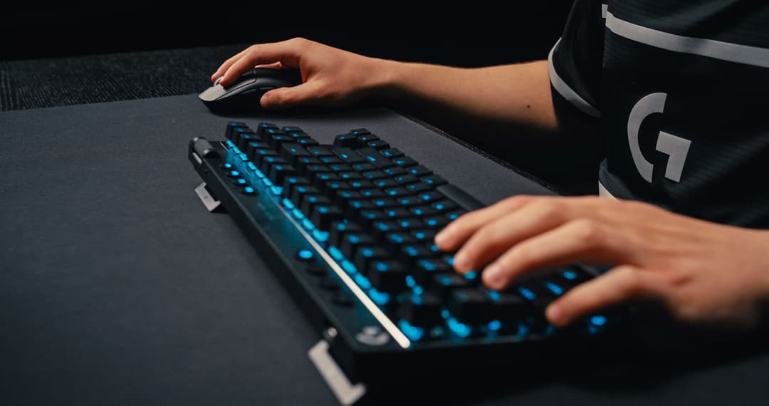 Clavier mécanique Logitech G PRO noir avec touches rétroéclairées bleu utilisé par un joueur à côté d'une souris
