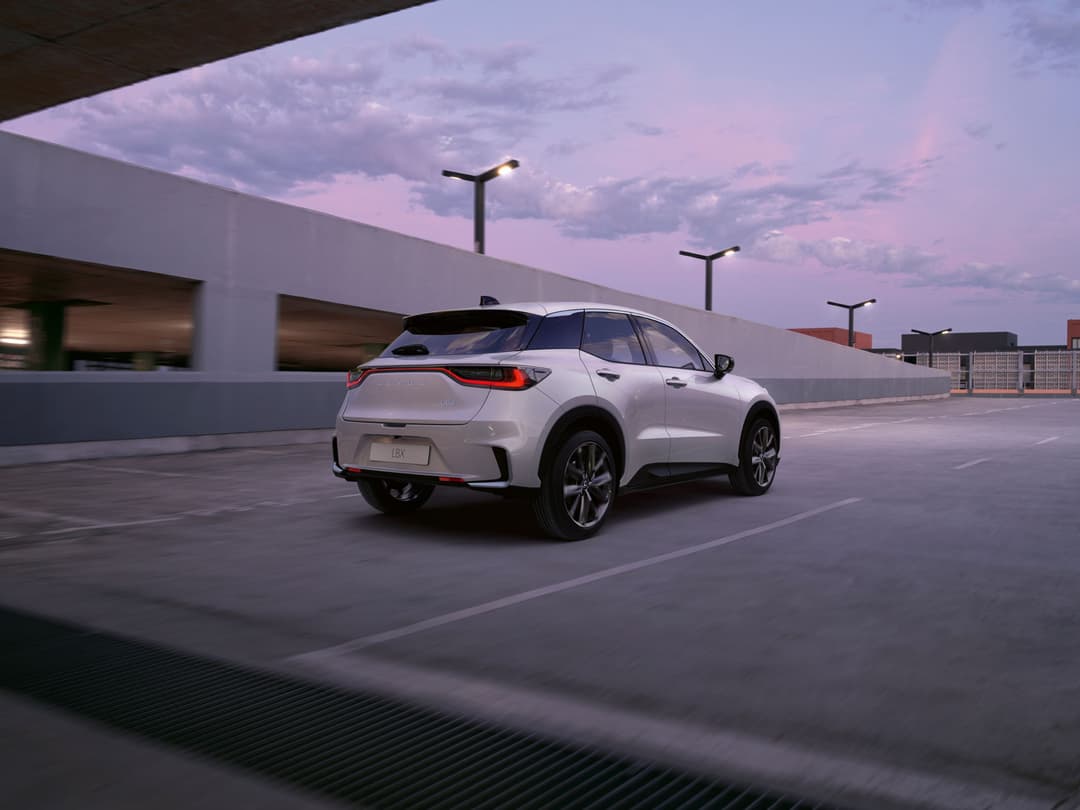 Subaru LBX blanc garé sur un parking urbain, vue de trois quarts arrière montrant les jantes de 18 pouces et la silhouette compacte