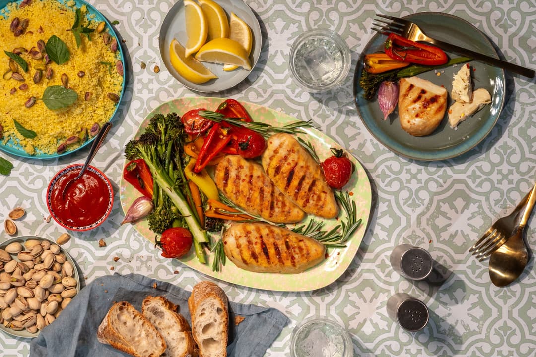 Filets de poulet végétal Planted grillés avec marques de cuisson, servis sur assiette avec légumes, citron et herbes aromatiques
