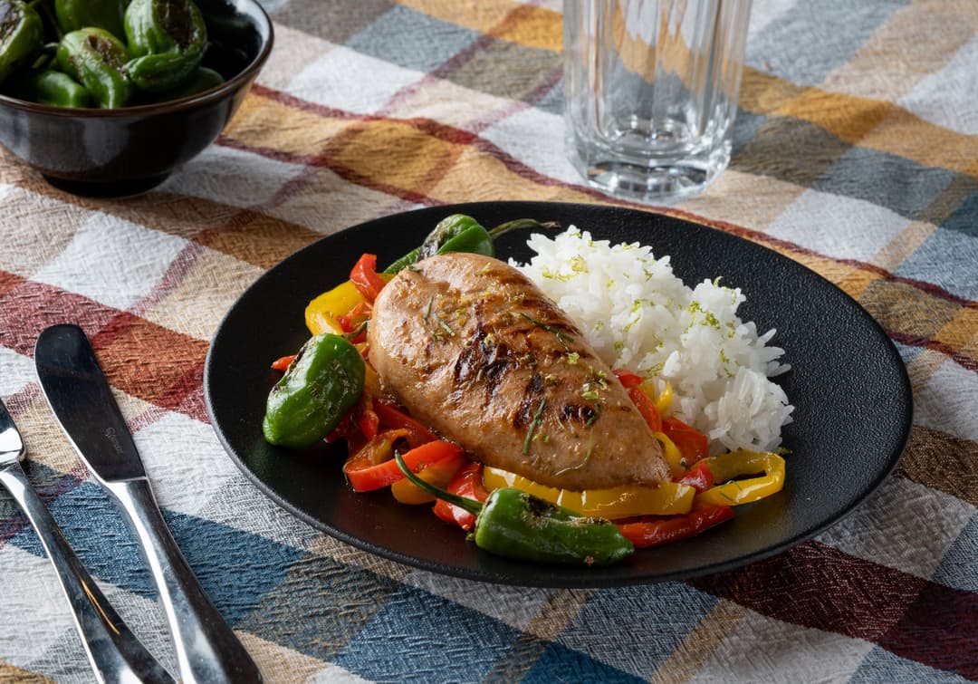 Filet de poulet végétal Planted doré à la poêle, servi sur lit de poivrons, accompagné de riz blanc et légumes verts