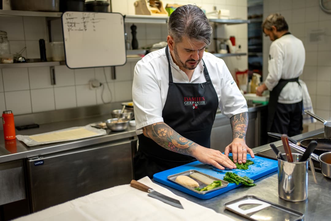 Chef Damien Germanier prépare un filet de poulet végétal Planted en cuisine, sur une planche bleue