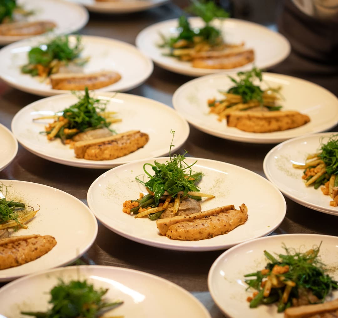 Filets de poulet végétal Planted présentés sur des assiettes blanches avec frites et microplantes vertes