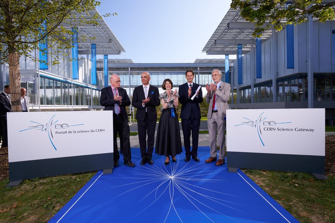 Inauguration du Portail de la science du CERN, avec cinq personnalités officielles devant deux panneaux bleus et blancs du centre de communication, bâtiments modernes en arrière-plan
