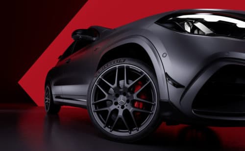 Détail de jante AMG dix rayons mat bicolore Polychrome sur SUV compact Mercedes-AMG gris foncé sur fond rouge