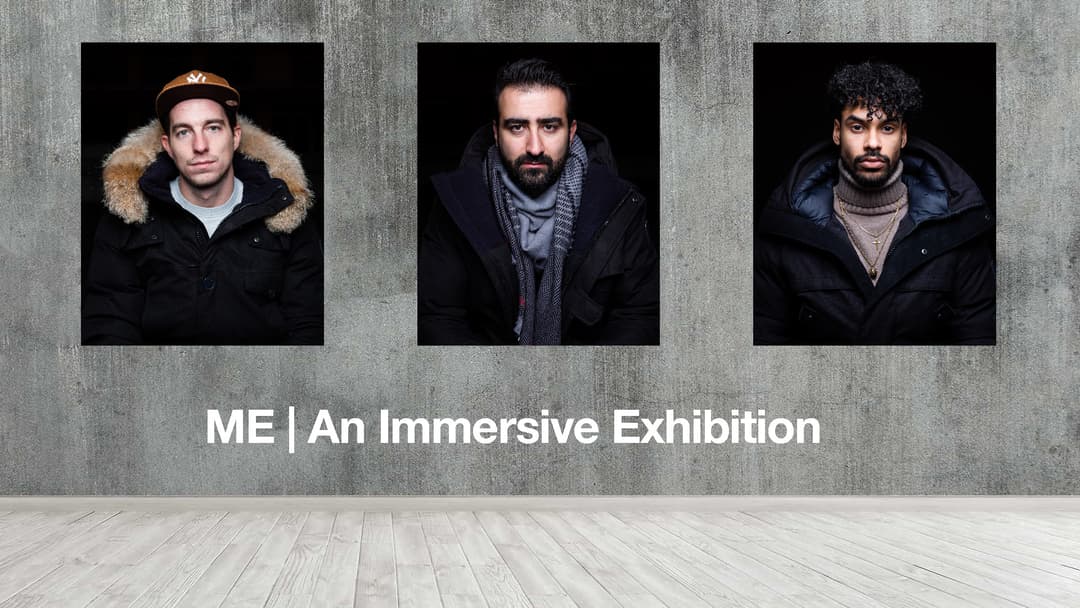 Trois portraits d'hommes avec expression neutre sur fond noir, affichés sur mur gris béton avec le texte « ME | An Immersive Exhibition »