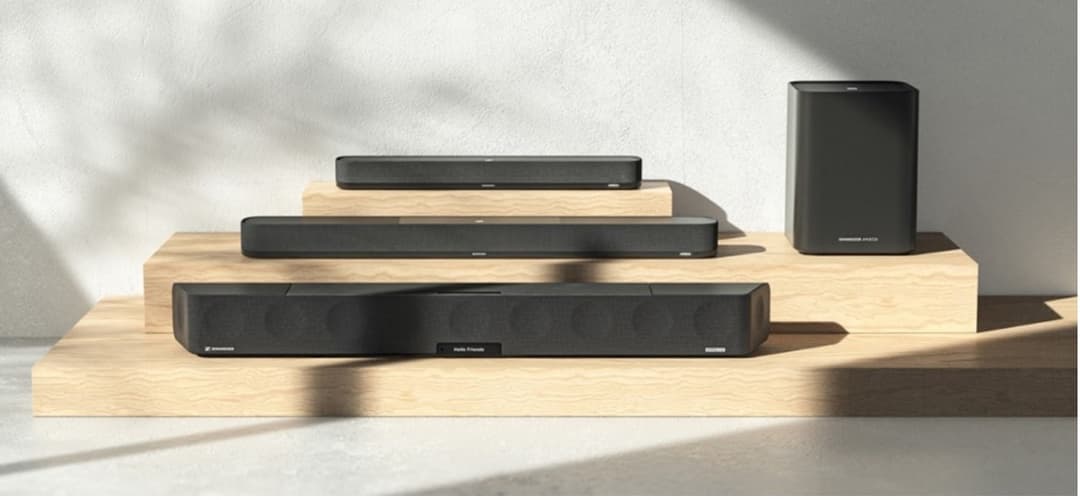 Barres sonores et enceinte Sennheiser noires présentées sur des socles en bois clair