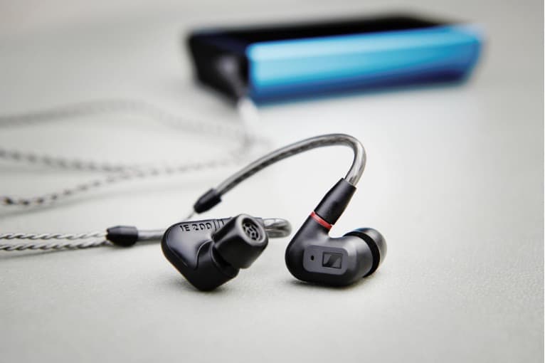 Écouteurs intra-auriculaires noirs avec câble tressé blanc et barres de son Sennheiser AMBEO floues en arrière-plan