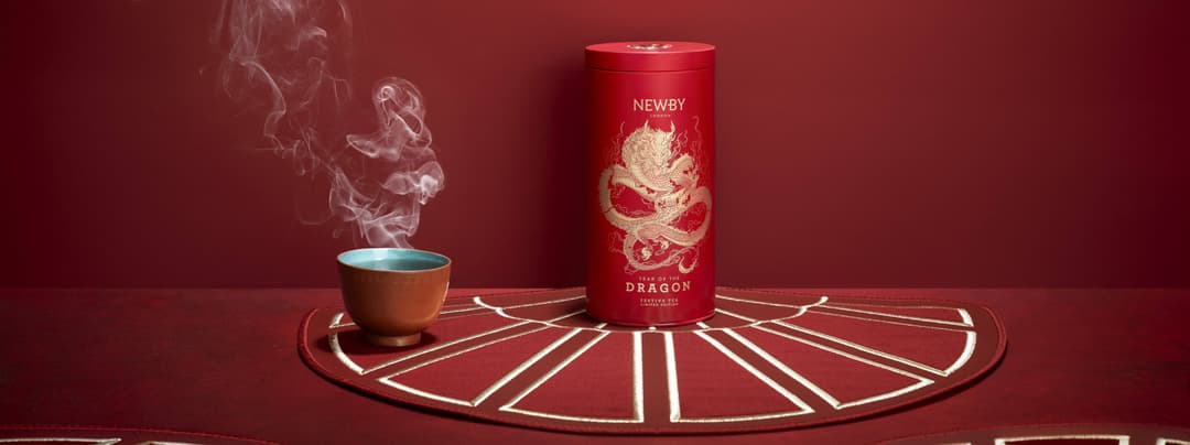 Boîte de thé Newby année du Dragon en rouge et or, avec une tasse fumante sur un tapis décoratif