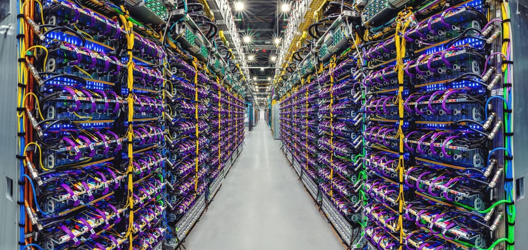 Rangée de serveurs TPU v5p illuminés de LED bleues et violettes dans un centre de données Google
