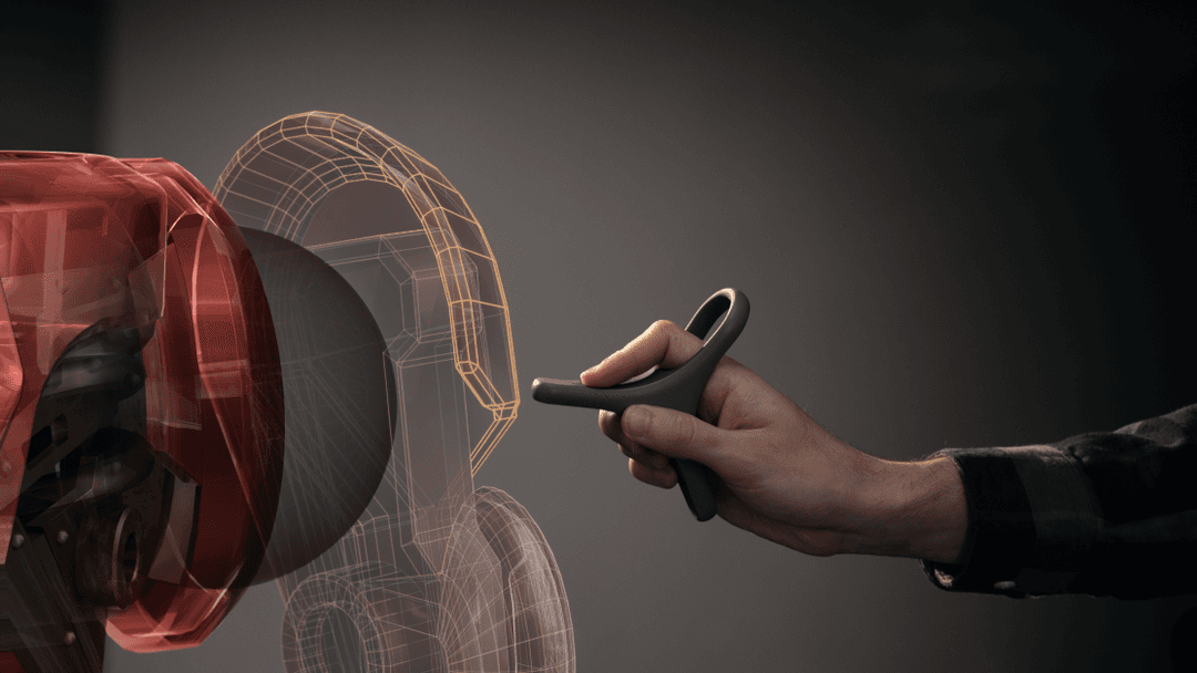 Main tenant un contrôleur noir de pointage face à un modèle 3D rouge et filaire projeté dans l'espace virtuel