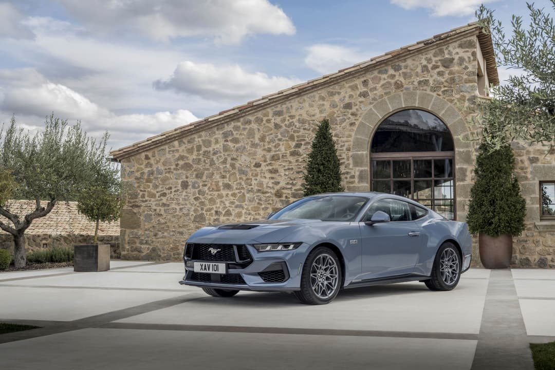 Nouvelle Ford Mustang bleue garée devant un bâtiment en pierre, design sportif et moderne