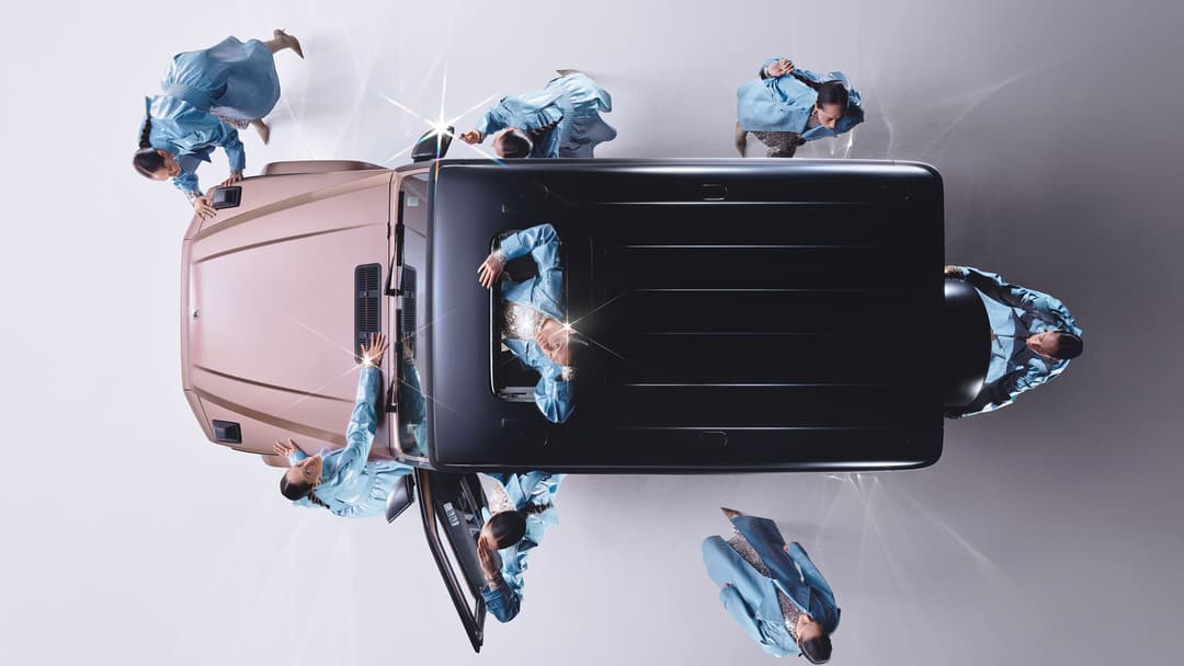 Mercedes-Benz Classe G STRONGER THAN DIAMONDS Edition vue de dessus, de couleur noir et rose, entourée de personnes en tenue bleue