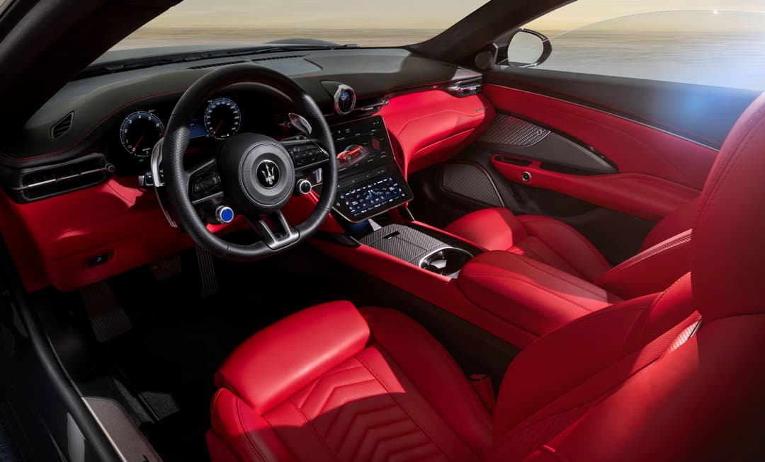 Intérieur de la Maserati GranCabrio avec sièges et moquette rouge, volant noir et écran tactile central