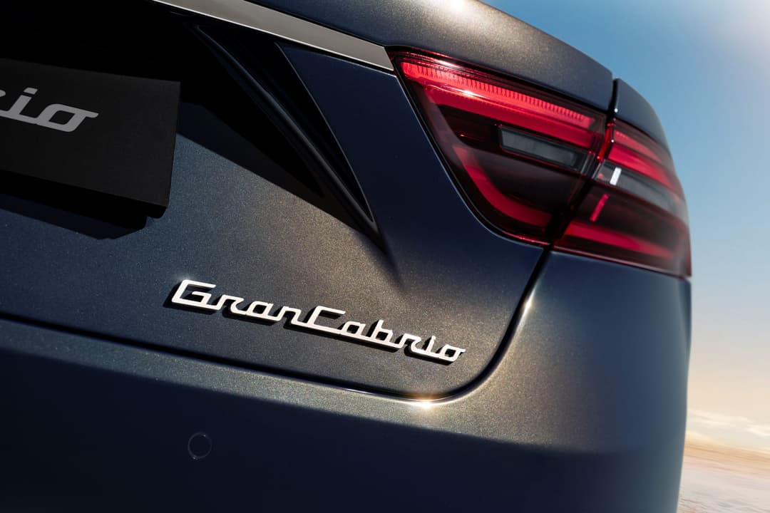 Arrière de la Maserati GranCabrio gris anthracite avec badge chromé et feux rouges, sous ciel bleu