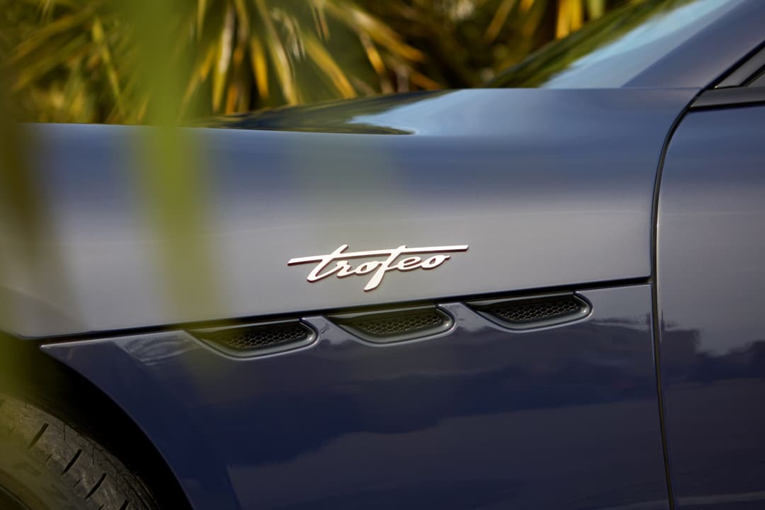 Détail du flanc de la Maserati GranCabrio, montrant le badge Trofeo et les trois sorties d'air chromées, carrosserie bleu foncé